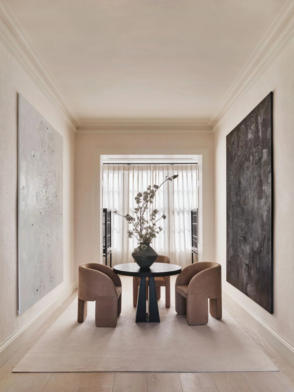 Quiet interior corridor with large artworks, a central table and soft natural light